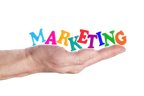 A person's hand holding the word marketing, emphasizing its importance for your business.