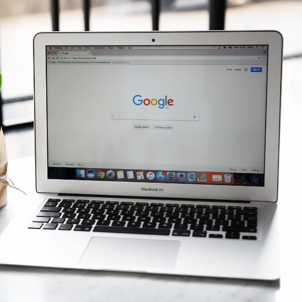 A laptop is sitting on a table next to a cup of coffee, creating a perfect environment for productive work or relaxation with just one spot for all your Google My Business needs.